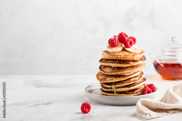 Fototapeta Stack of homemade pancakes with fresh raspberries on light concrete background, copy space
