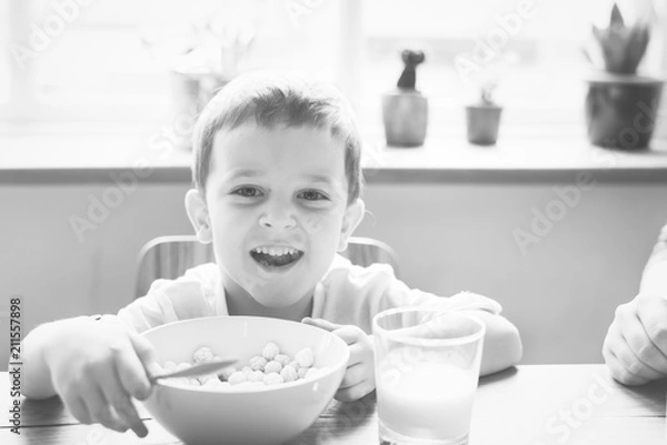Fototapeta Little boy smiling while eating his breakfast