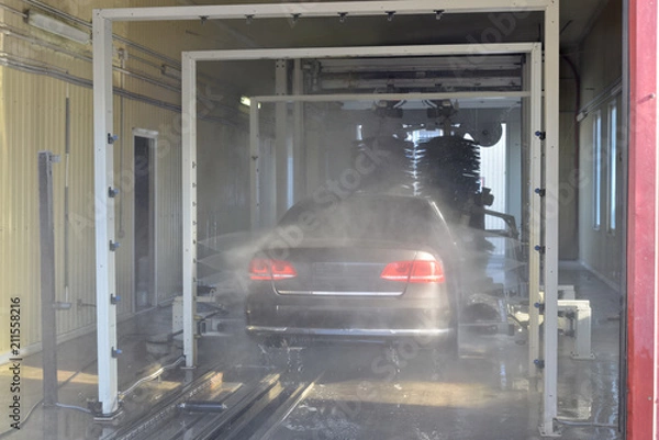 Fototapeta Auto being washed in a high pressure rinse arch in an automatic car wash facility