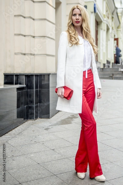Fototapeta Fashionable young blonde in a spring fashionable suit and with a shopping bag in the center of Moscow
