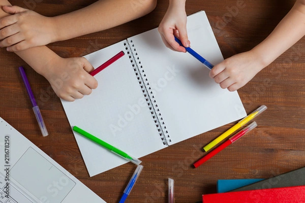 Fototapeta Children do homework at the table. Kids draws on a blank sheet of paper. Preschoolers do homework together. Boy and girl writing a letter.