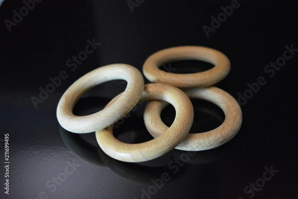 Obraz On a black glossy background there are four wooden rings of brown color with reflection