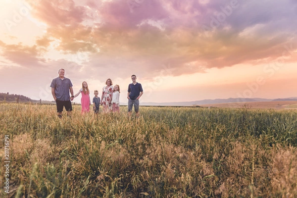 Fototapeta Family walking in a field in a sunset quality family time