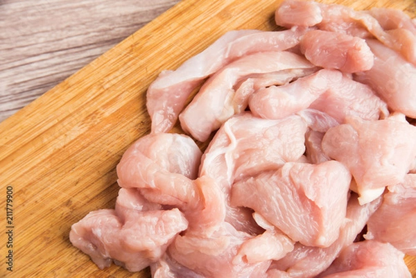 Obraz Sliced fresh chicken fillets on a wooden cutting board