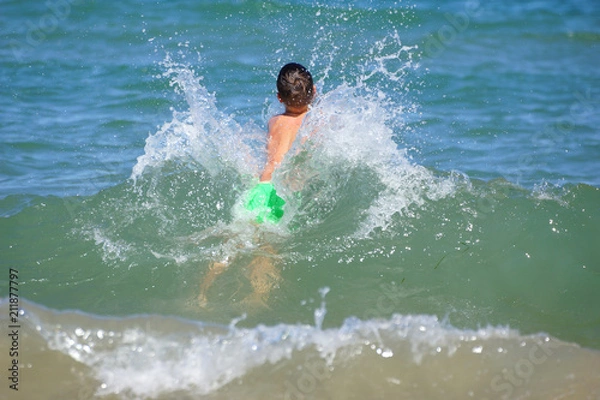 Fototapeta Happy little boy run play with waves on beach of Mediterranean