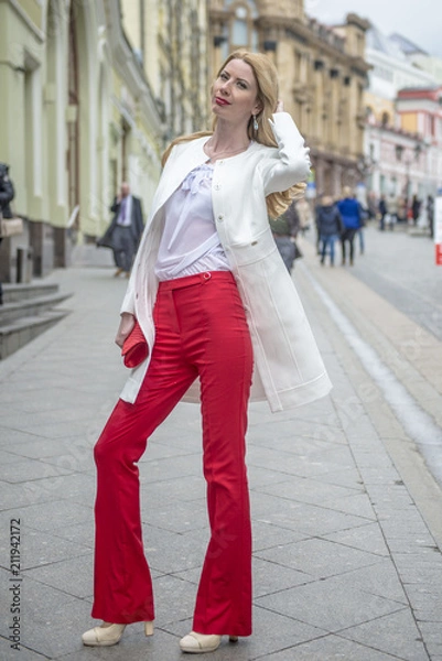Fototapeta Fashionable young blonde in a spring fashionable suit and with a shopping bag in the center of Moscow
