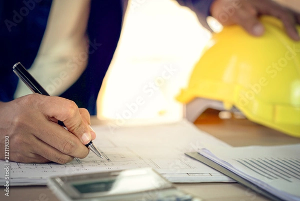 Fototapeta Engineer and architect working document about progress of work schedule and construction drawing on the site