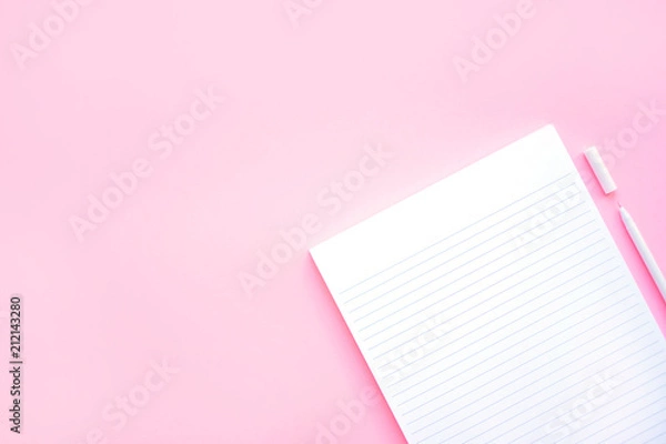 Fototapeta Beautiful office stationery flatlay with ruled notebook and white pen on the bright desk with pink background.