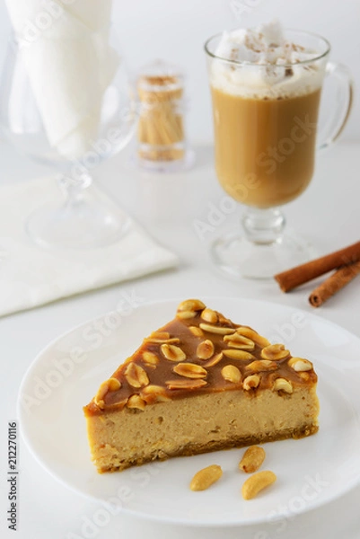 Fototapeta Slice of caramel cake with peanuts and a cup of coffee with cream