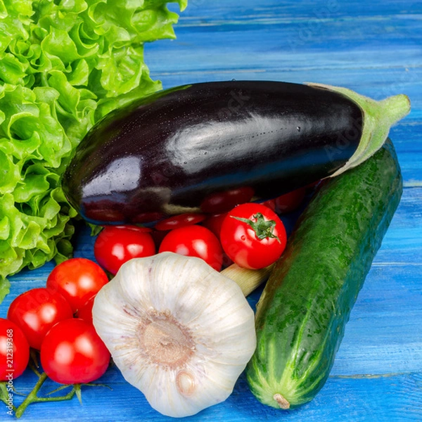 Fototapeta Different raw vegetables lies in a heap on a blue wooden table. For instagram format. Square.
