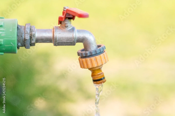 Fototapeta open water faucet or tap with flowing water in blur garden background