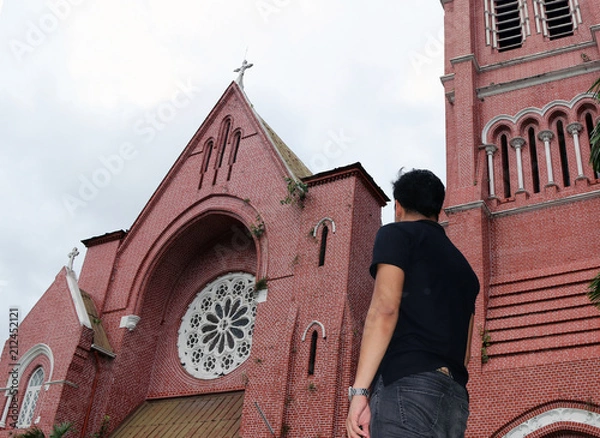 Fototapeta Behind of the man standing in front of the main building of church and church tower at cathedral of the holy trinity, the church of the province of Myanmar.