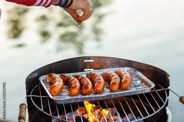 Fototapeta Grilled sausage on the flaming grill, close up