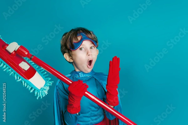 Fototapeta Portret młodego chłopca czyszczenia superbohatera trzymać mopa na niebieskim tle
