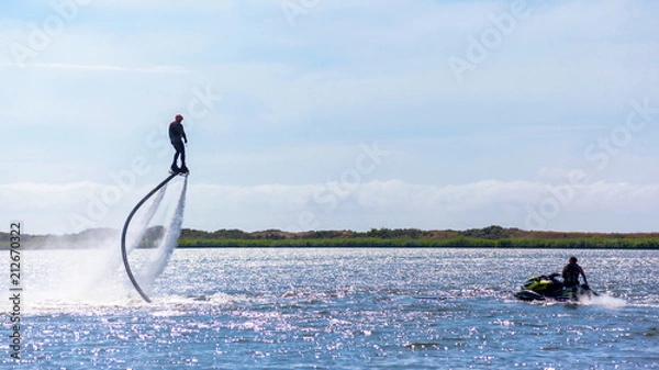 Fototapeta a man is riding a flyboard on a lake on a sunny day