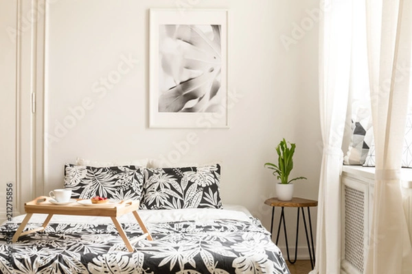 Fototapeta Wooden tray with breakfast on a double bed with floral bedding in a hotel room interior