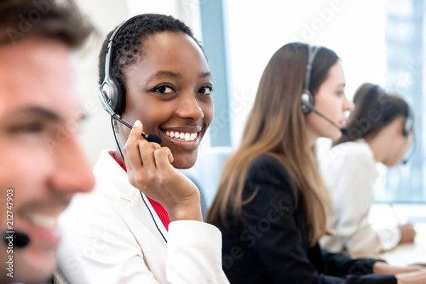 Obraz Uśmiechnięta piękna African American kobieta pracująca w call center z różnorodnym zespołem