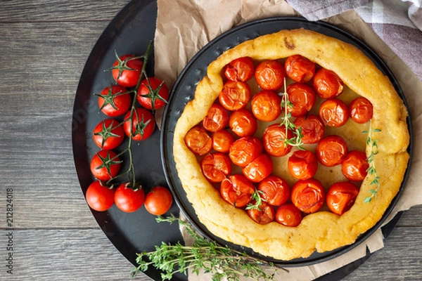 Fototapeta Homemade tart with cherry tomatoes of puff pastry with raw tomatoes and thyme on  dark wooden background. Tomatoes tart tatin. Rustic style.