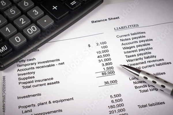 Fototapeta balance sheet on a white sheet of paper, calculator and pen