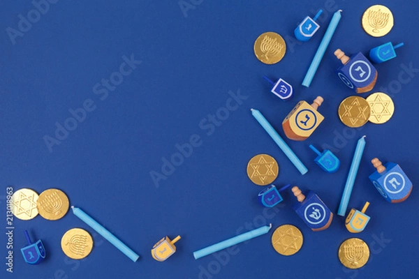 Fototapeta Dark blue background with multicolor dreidels and chocolate coins. Hanukkah and judaic holiday concept.
