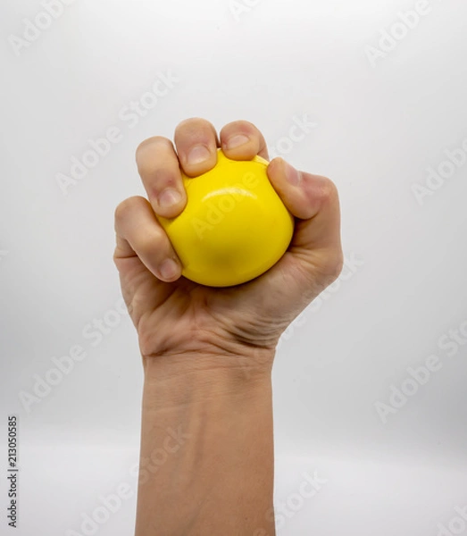 Obraz Hand holding yellow stress ball isolated on white