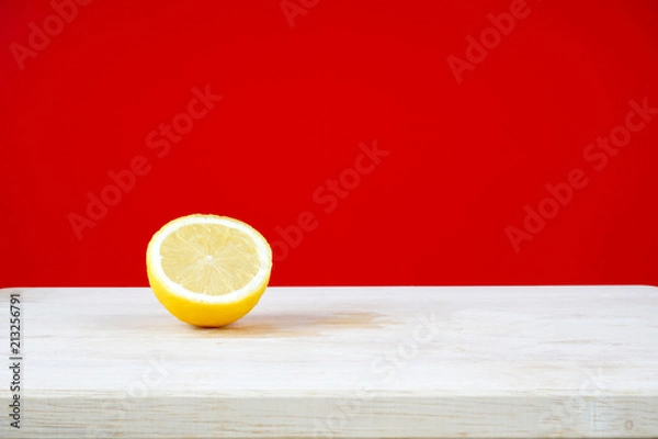 Obraz Lemon on a wooden table over red background