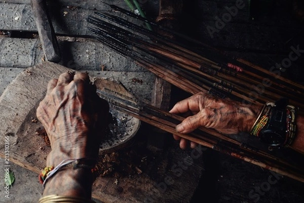 Obraz Muara Siberut, Mentawai Islands / Indonesia - Aug 15 2017: Tribal elder Toikot poisoning arrowheads for hunting at his jungle home