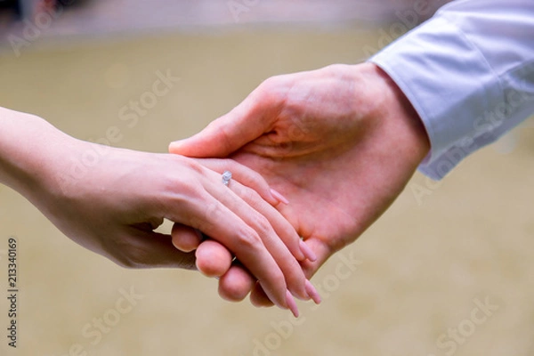 Fototapeta Bride and groom holding hands in wedding celemony.