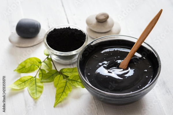 Obraz Homemade facial mask and scrub by activated charcola powder and yogurt on white wooden background