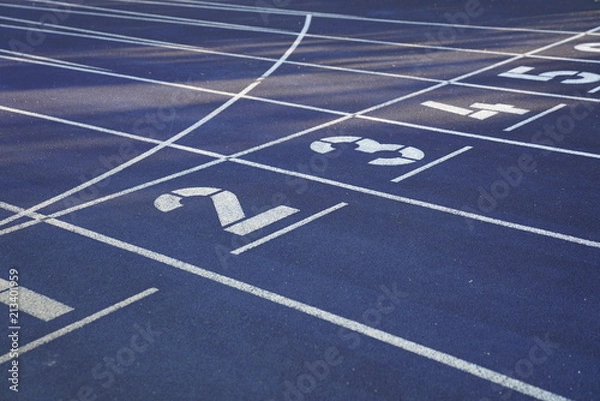 Fototapeta Start positions of a blue outdoor stadium running track with white dividing lines