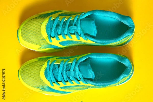 Fototapeta Pair of sport shoes on colorful background. New sneakers on yellow background, copy space. Overhead shot of running shoes. Top view, flat lay