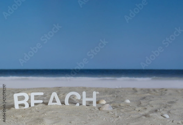 Fototapeta The word beach in white wooden letters in the sand on the beach