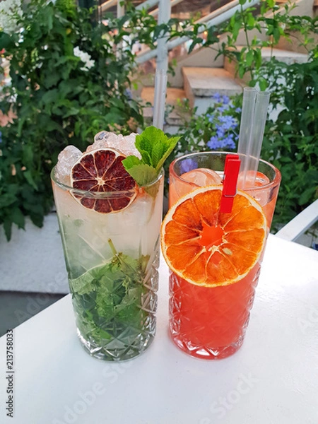 Fototapeta Set of alcohol cocktails in a bar. Green MOJITO cocktail and CAMPARI orange.