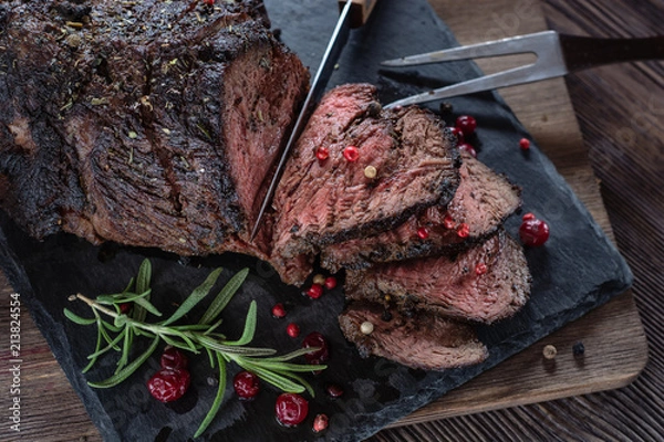 Fototapeta Appetizing roast beef with sauce and spices on a wooden table