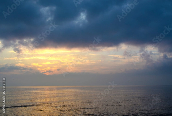 Obraz Light mood with orange illuminated clouds during a sunrise over the Baltic Sea in Bansin on usedom, Germany