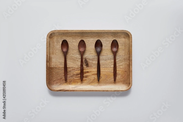 Fototapeta top view of wooden tray with wooden spoons on white table, minimalistic concept