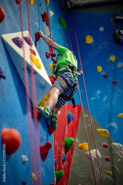 Obraz Young boy climbing up on practice wall in indoor rock gym