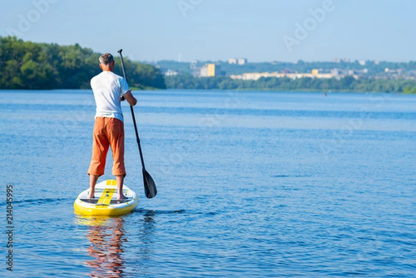 Obraz Man paddling on a SUP board
