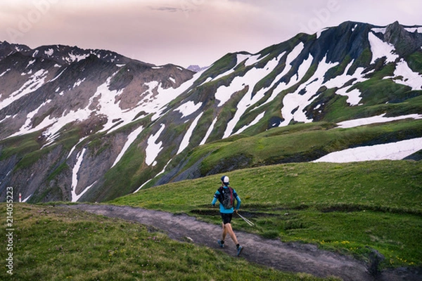 Fototapeta A trail runner running through the mountains at sunset