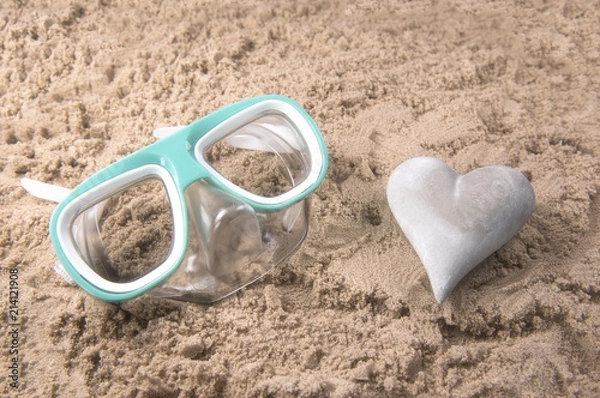 Fototapeta Beach background image of a snorkel set and a heart shaped stone on a sandy beach 