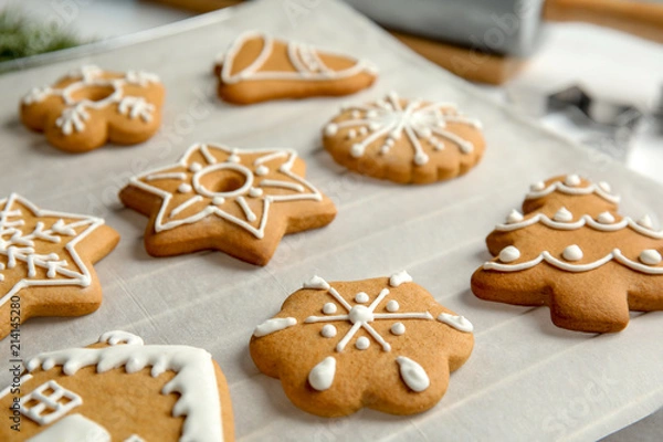 Fototapeta Tasty decorated Christmas cookies on baking parchment
