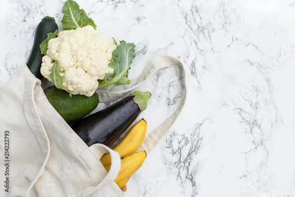 Obraz Set of products in a cotton eco bag on a marble table, bananas, avocado, eggplant, zucchini, cauliflower. The concept of zero waste. copy space.