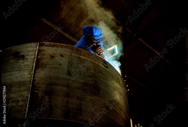 Fototapeta Arc Welder working on a furnace unit in a German Machine Factory.