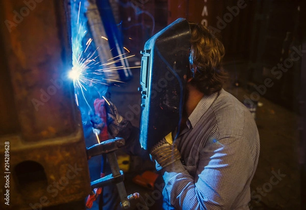 Fototapeta Arc Welder working on a furnace unit in a German Machine Factory.