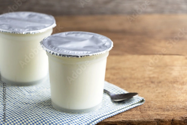 Obraz A breakfast of yogurt with a spoon placed on a wooden table.