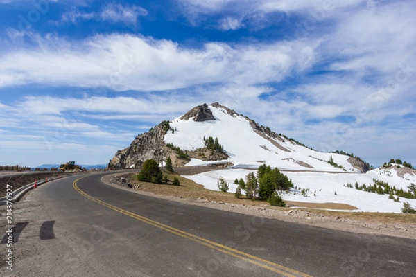 Fototapeta A scenic highway (Rim Drive) with the rocky mountain (Watchman Peak) background in Crater Lake National Park, Oregon, USA