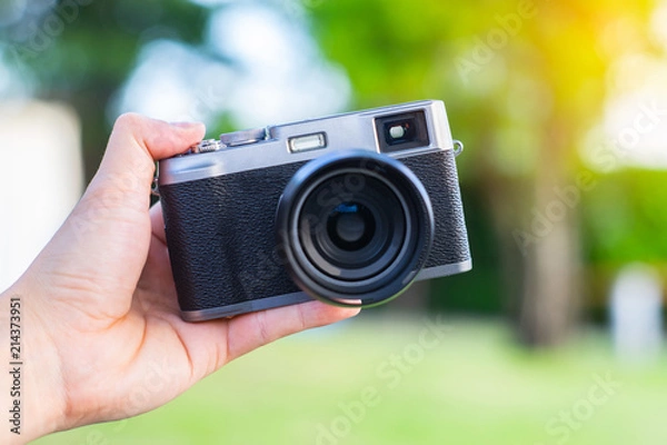 Fototapeta Soft focus photo of retro-style rangefinder camera. Black-and-gray camera on hand.
