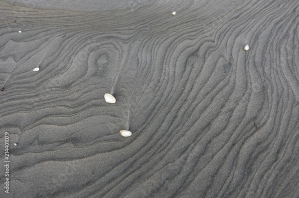 Fototapeta Tide patterns on the surface of a grey, sandy beach in the South Island of New Zealand. A few sea shells are scattered on the surface. 