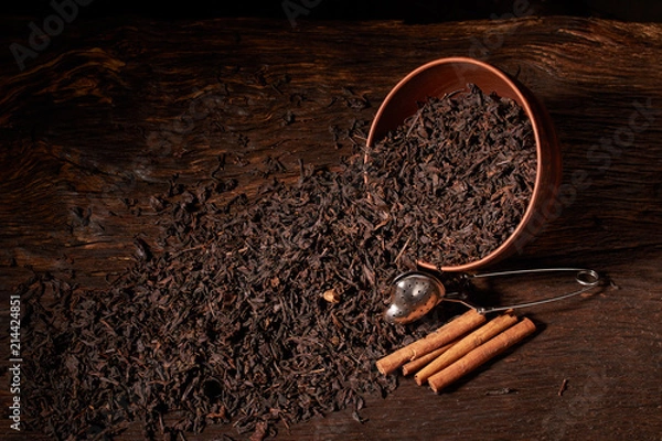 Obraz Top view of dried black tea in clay bowl on wooden table. Concept of tea production. Macro, close up