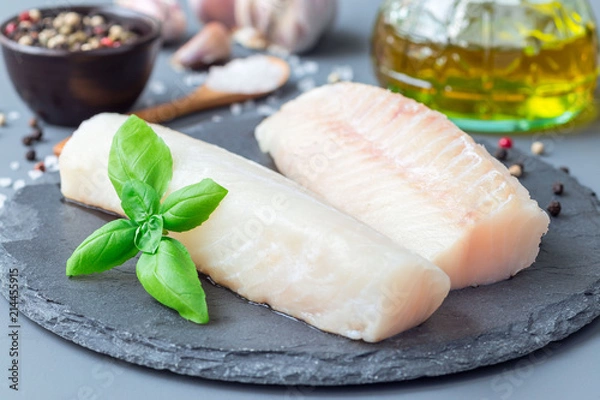 Obraz Świeży filet z dorsza z przyprawami, pieprzem, solą, bazylią na kamiennym talerzu, poziomy